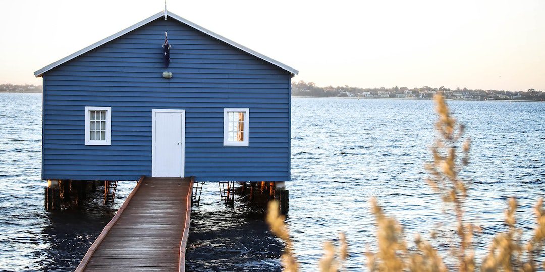 House With Dock on Body of Water Under Blue and White Sky
